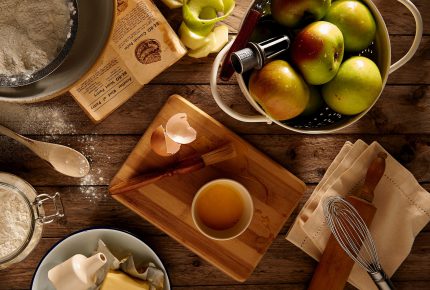 rustic image of a bowl of apples and cooking supplies
