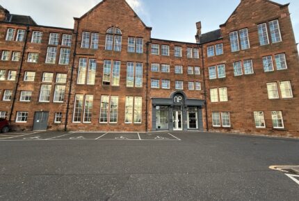 Image of red sandstone buildling with sunlight hitting the windows and the letter NP above the door