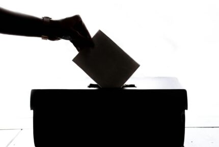 silhouette of hand placing a ballot paper in a ballot box